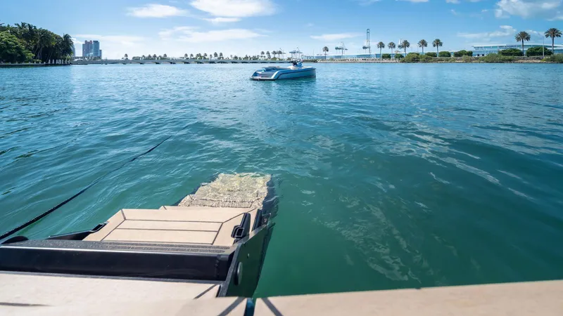 Slide: The Image of 2024 Vanquish Yachts VQ58 on serene water with distant cityscape and palm trees. - 8
