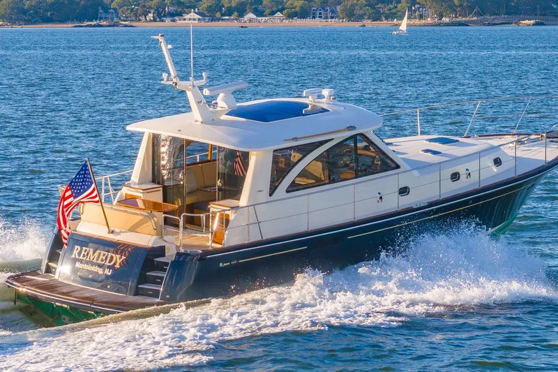 The Image of 2014 Hunt Yachts 44 cruising on water, displaying American flag, sunny day. - 0