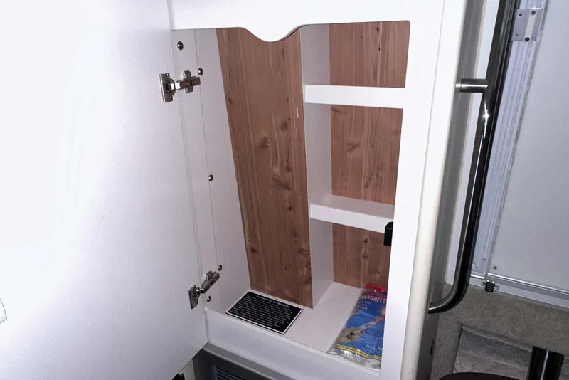 Slide: The Image of Open cabinet in 2022 Formula 350 Sun Sport boat, featuring wooden shelves and a brochure. - 36