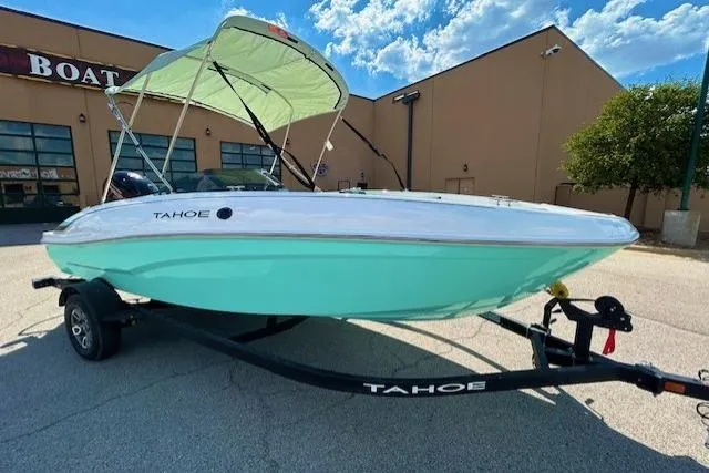 The Image of 2026 Tahoe T18 boat with canopy on trailer, parked outside a building under a blue sky. - 0