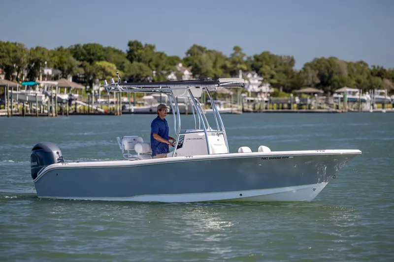 Slide: The Image of 2020 Sea Hunt Triton 210 boat cruising on a sunny day near a marina. - 2