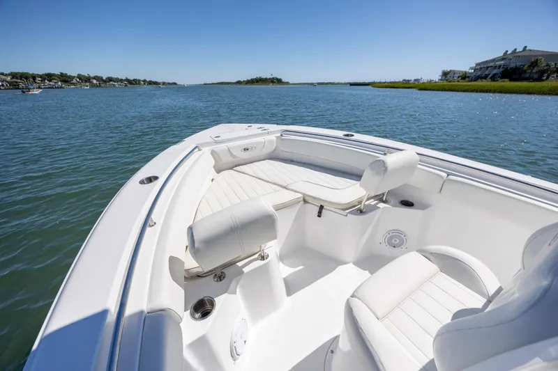 Slide: The Image of 2020 Sea Hunt Triton 210 boat interior on calm water, featuring white seating and clear blue sky. - 21