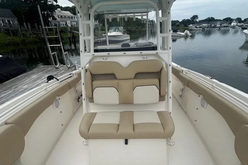 Slide: The Image of 2020 Key West Billistic 261 Center Console boat interior with beige seating, docked by calm waters. - 13