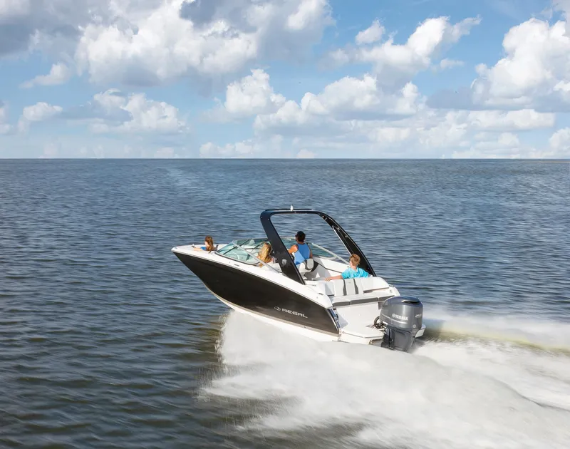Slide: The Image of 2022 Regal 23 OBX boat cruising on a calm lake near waterfront homes. - 2