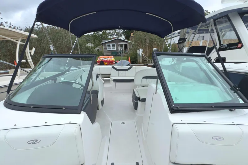 Slide: The Image of 2022 Regal 23 OBX boat with dual windshields and blue canopy, docked outdoors. - 37