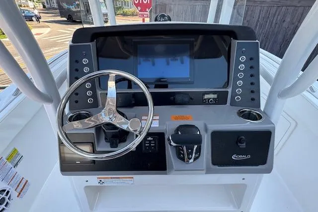 Slide: The Image of 2026 Robalo R230 Center Console boat dashboard with steering wheel and electronic controls. - 9