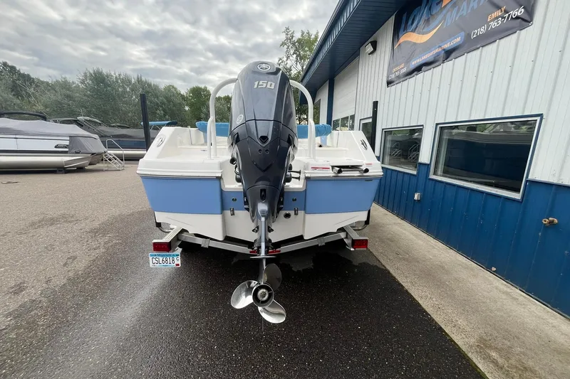 Slide: The Image of 2023 Robalo R200 Center Console boat with Yamaha 150 engine, parked outside a marine shop. - 19