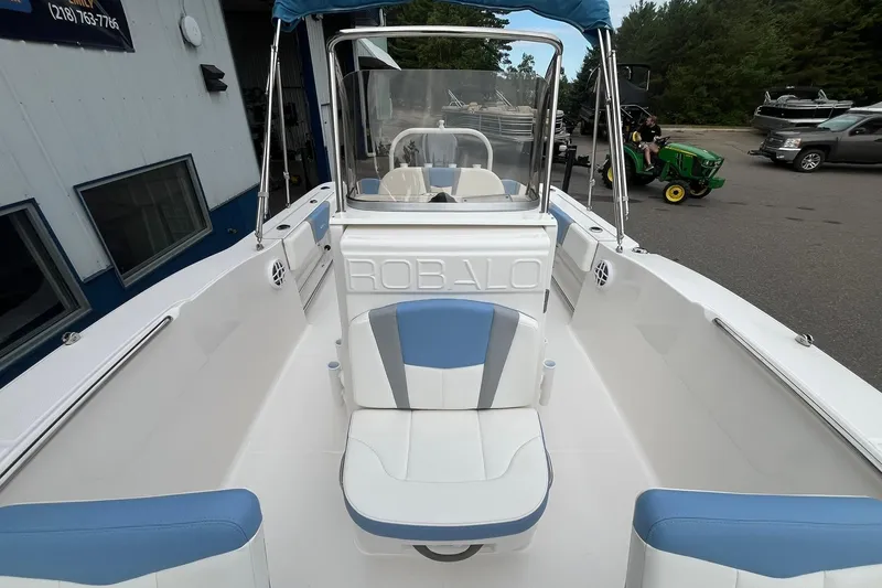 Slide: The Image of 2023 Robalo R200 Center Console boat with blue and white seating, docked outdoors. - 31