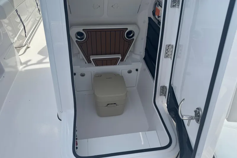Slide: The Image of 2026 Edgewater 230CC boat interior with compact toilet and storage area. - 19