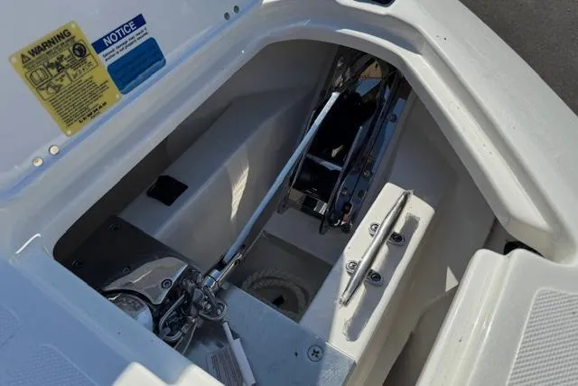 Slide: The Image of 2026 Pursuit S 268 Sport boat anchor compartment with warning labels and mechanical components. - 15