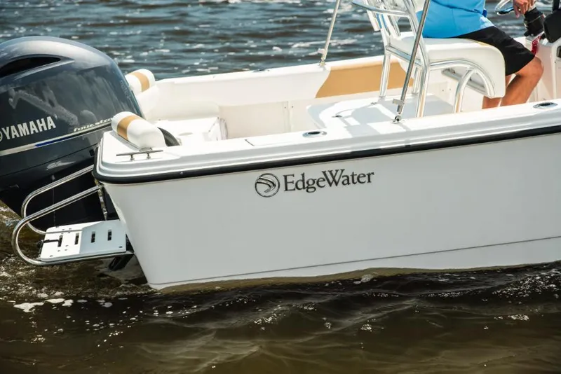 Slide: The Image of 2026 Edgewater 188CC boat interior with seating and console, parked outdoors. - 8