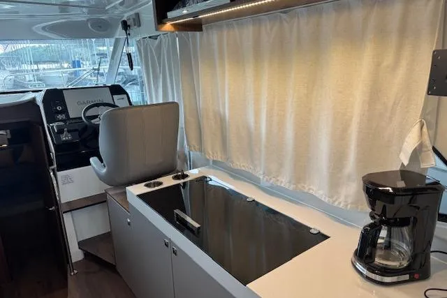 Slide: The Image of Interior of 2025 Beneteau Antares 11 Fly, featuring helm, stove, and coffee maker. - 6