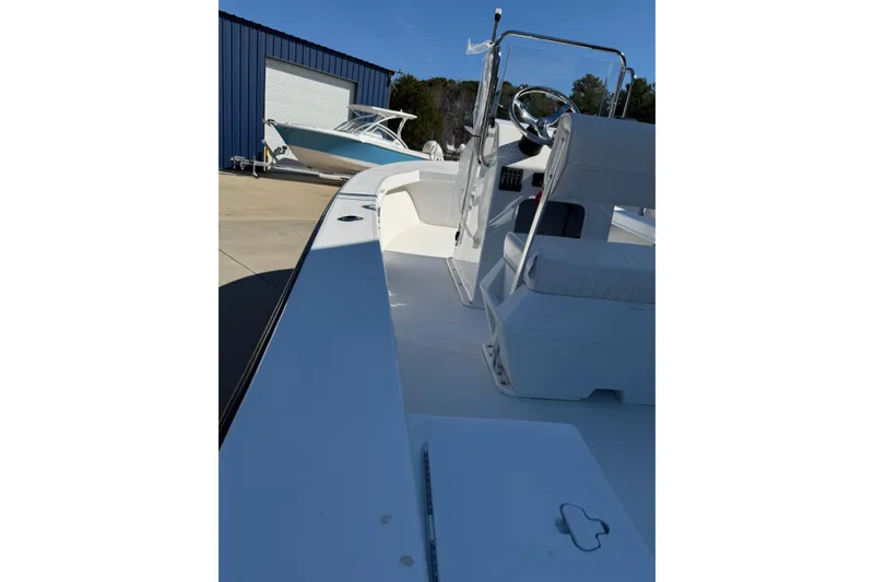 Slide: The Image of 2026 C-Hawk 18 Center Console boat, white interior, parked near blue building. - 16