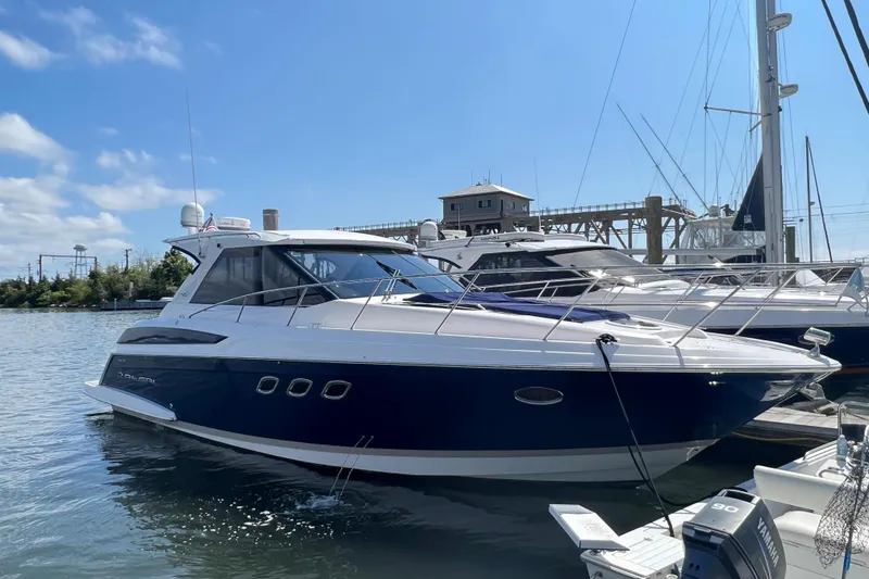 The Image of 2011 Regal 42 Sport Coupe yacht docked in a marina under clear blue skies. - 1