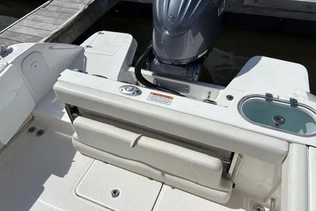 Slide: The Image of 2022 Edgewater 230CC boat interior with motor and seating, docked at marina. - 15