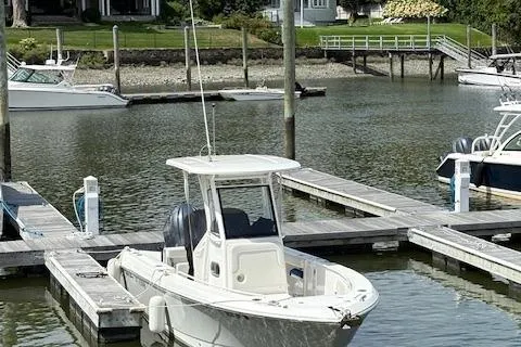 Slide: The Image of 2022 Edgewater 230CC boat docked in a serene marina setting. - 2