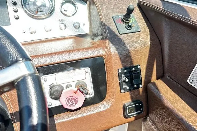 Slide: The Image of 2016 Regal 2800 Bowrider dashboard with controls and key fob on brown panel. - 5