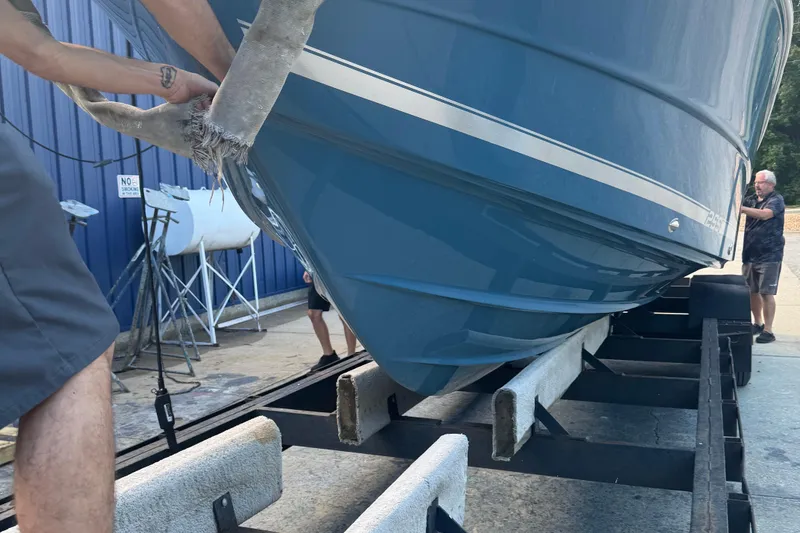 Slide: The Image of 2026 Bulls Bay 255 boat on trailer, blue hull, being maneuvered by two people. - 4