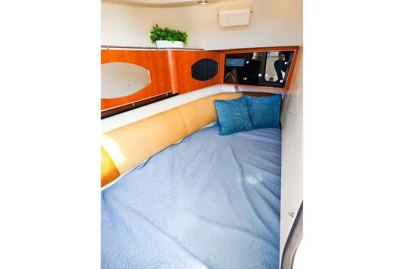 Slide: The Image of 2015 Grady White 335 Freedom cabin interior with bed, blue bedding, and decorative pillows. - 33