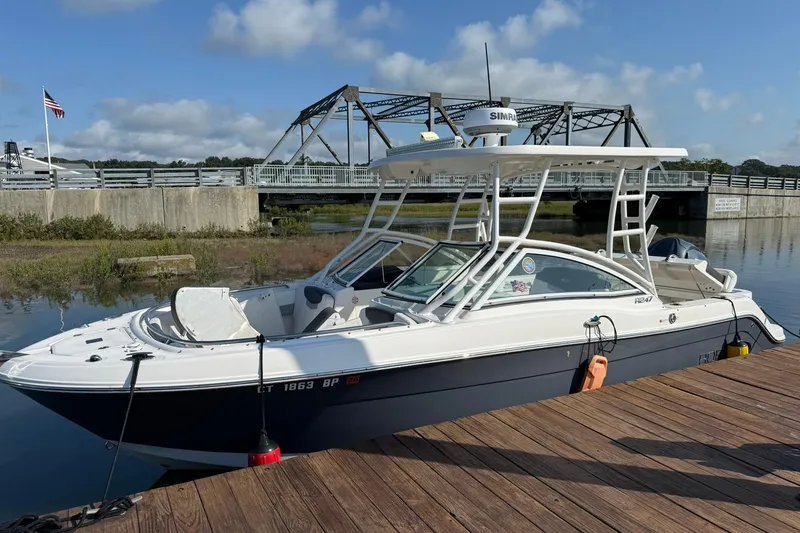 The Image of 2022 Robalo R247 Dual Console boat docked near a bridge on a sunny day. - 1