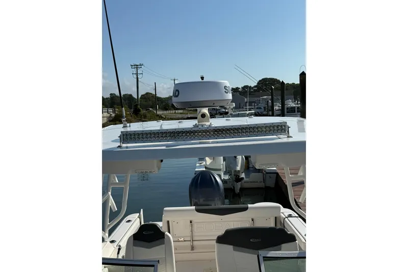 Slide: The Image of 2022 Robalo R247 Dual Console boat docked, featuring radar and seating area. - 5