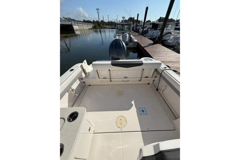 Slide: The Image of 2022 Robalo R247 Dual Console boat docked, showcasing spacious deck and seating area. - 9