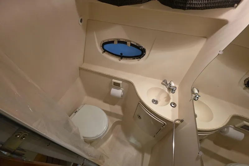 Slide: The Image of 2007 Regal 2860 Window Express boat bathroom with sink, toilet, and porthole window. - 11