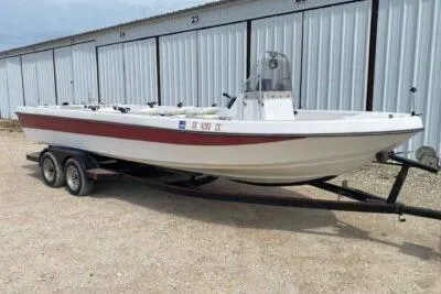 Slide: The Image of 2000 Falcon Striper boat on trailer, parked near storage units. - 2