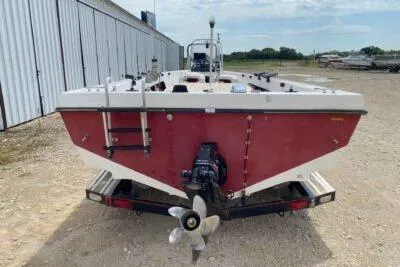 Slide: The Image of 2000 Falcon Striper boat with outboard motor, parked on a trailer in a gravel lot. - 6