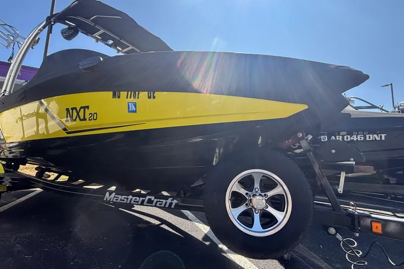 Slide: The Image of 2015 MasterCraft NXT20 boat in yellow and black on a trailer under sunlight. - 1