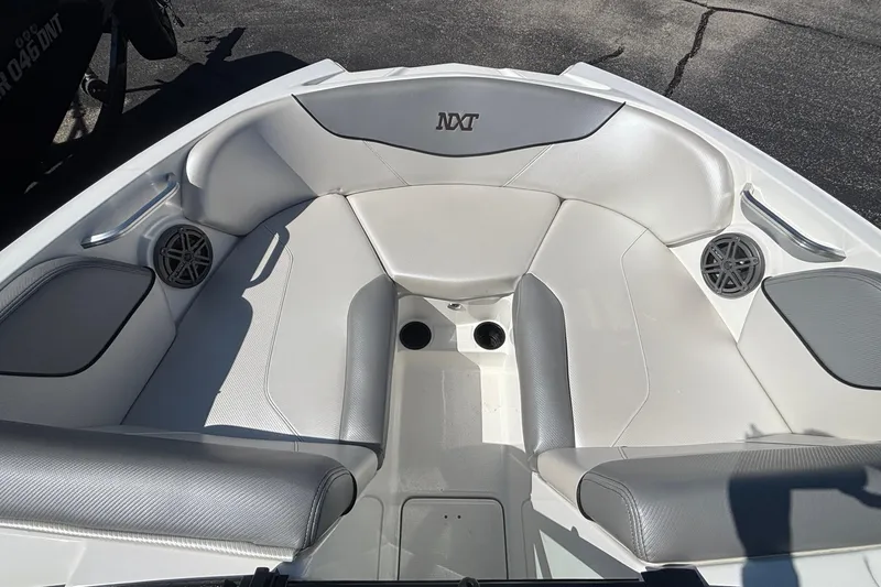 Slide: The Image of 2015 MasterCraft NXT20 boat interior with white and gray seating, featuring speakers and cup holders. - 16