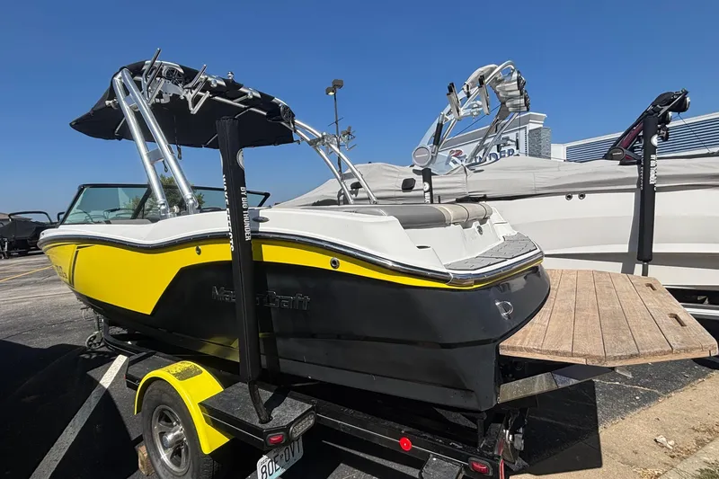 Slide: The Image of 2015 MasterCraft NXT20 boat with yellow and black design on a trailer. - 2