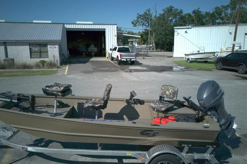 Slide: The Image of 2025 G3 15DK boat on trailer outside industrial building, featuring camo seats and Yamaha motor. - 11