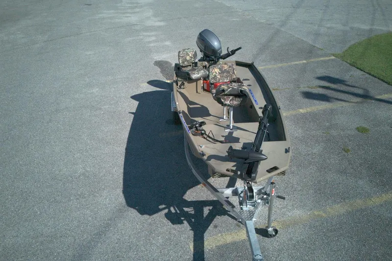 Slide: The Image of 2025 G3 15DK boat with camouflage seats on a trailer in a parking lot. - 3