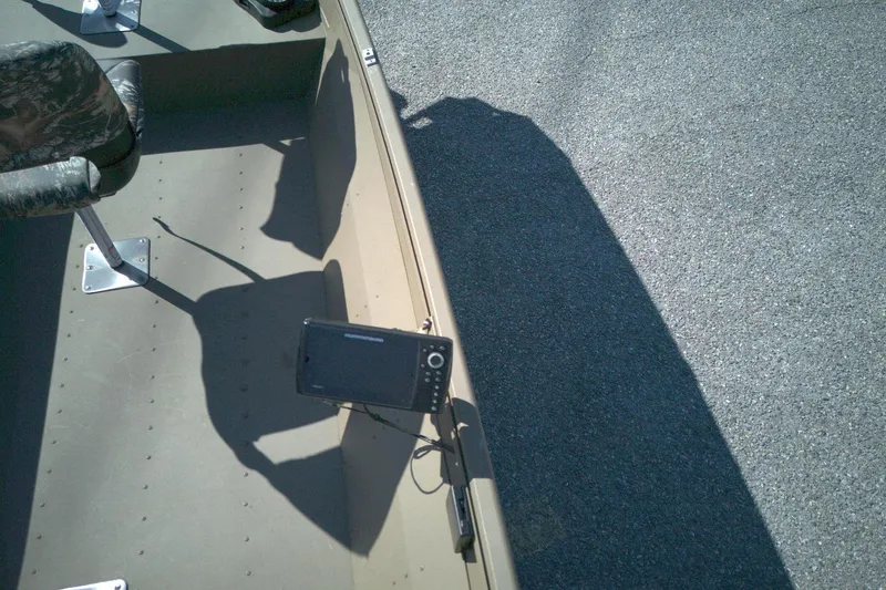 Slide: The Image of Boat interior with mounted electronic device, camo seats, and shadow on pavement. G3 15DK, 2025 model. - 9