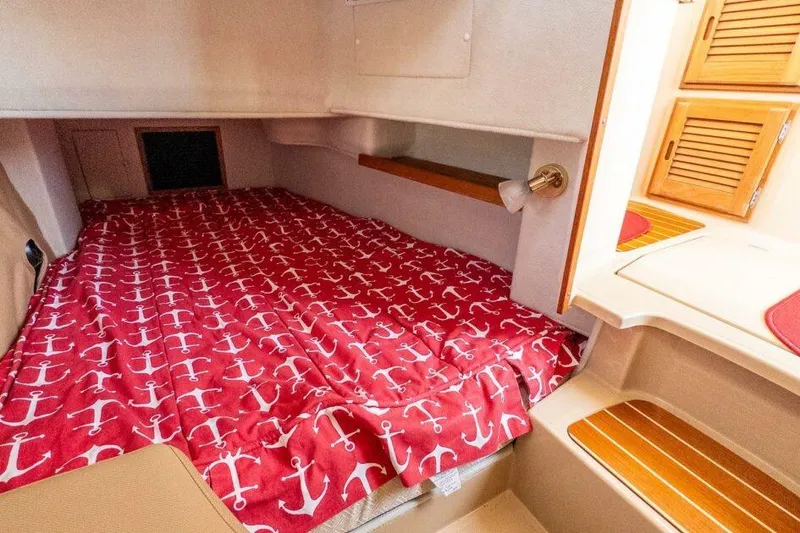 Slide: The Image of 2019 Ranger Tugs R-31-S cabin with anchor-patterned red bedding and wooden accents. - 13