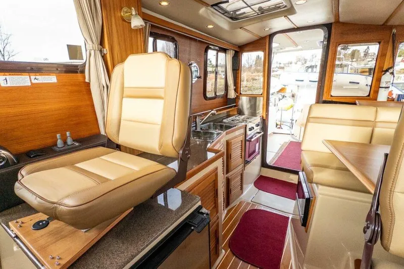 Slide: The Image of 2019 Ranger Tugs R-31-S interior with beige seating, kitchenette, and wooden accents. - 15