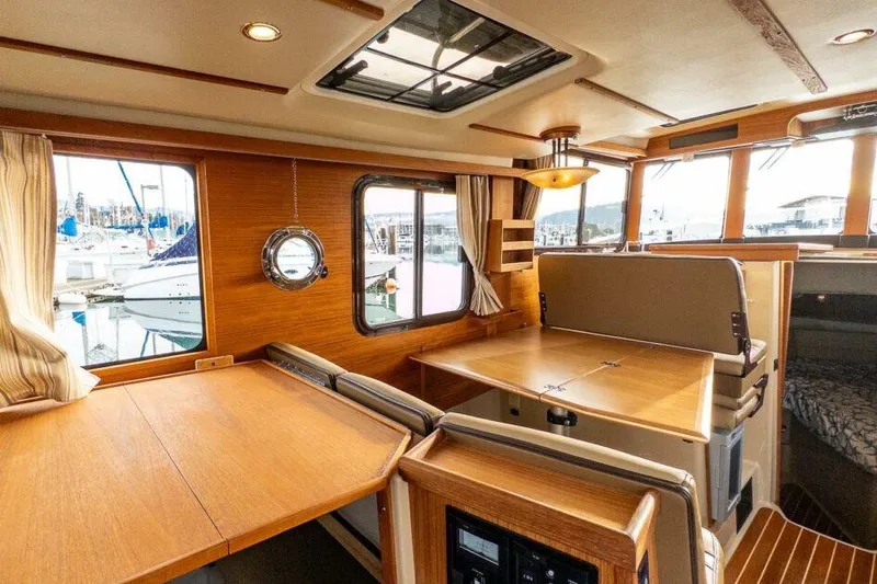 Slide: The Image of 2019 Ranger Tugs R-31-S interior with wooden dining area and marina view. - 19