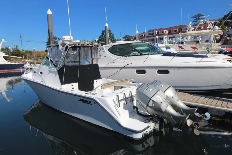Slide: The Image of 2001 Mako 293 Walk Around boat docked at marina with twin outboard engines. - 1