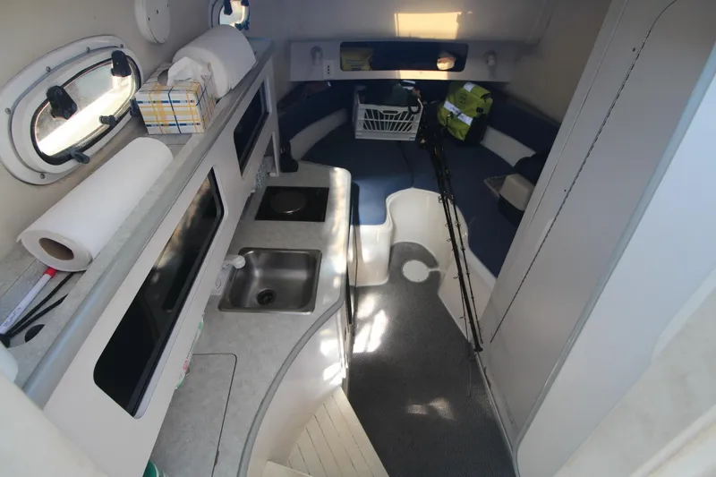 Slide: The Image of Interior of 2001 Mako 293 Walk Around boat with kitchenette and seating area. - 17