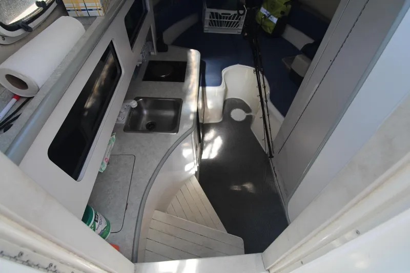Slide: The Image of Interior of 2001 Mako 293 Walk Around boat with kitchenette and seating area. - 18