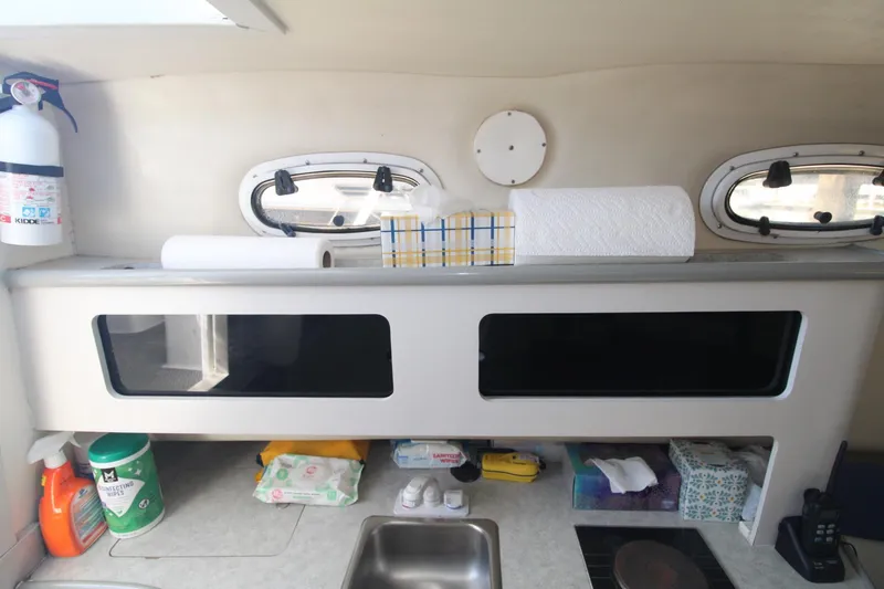 Slide: The Image of 2001 Mako 293 Walk Around boat interior with storage, cleaning supplies, and a small sink. - 21