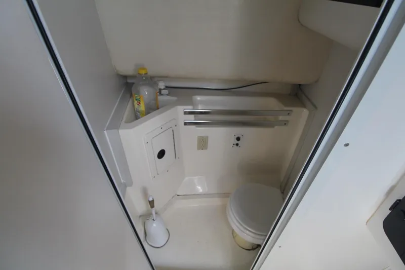 Slide: The Image of Compact bathroom in 2001 Mako 293 Walk Around boat, featuring toilet and storage. - 24