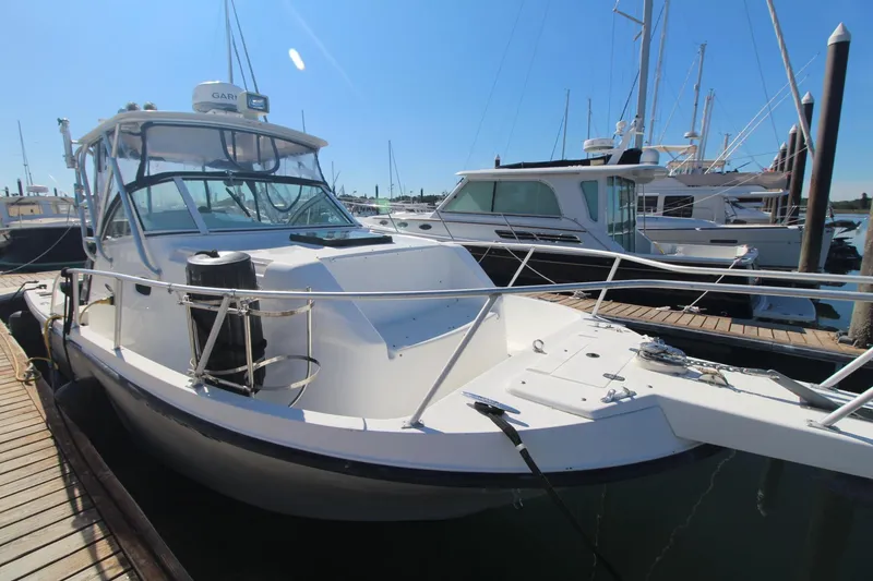 Slide: The Image of 2001 Mako 293 Walk Around boat docked at marina under clear blue sky. - 7