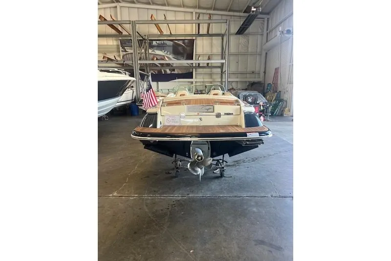 Slide: The Image of 2024 Chris-Craft Launch 27 boat in a warehouse, rear view with American flag. - 4