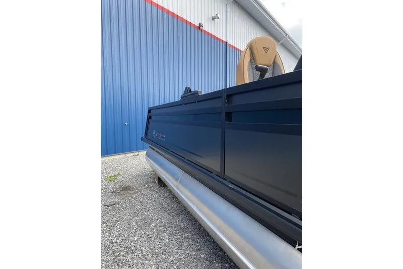 Slide: The Image of 2025 Viaggio Lago Z-S pontoon boat beside blue industrial building. - 7