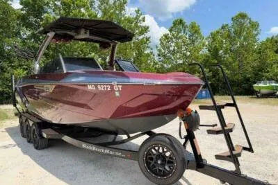 Slide: The Image of 2024 Tigé Ultré 25ZX boat on trailer, parked outdoors with trees in the background. - 1