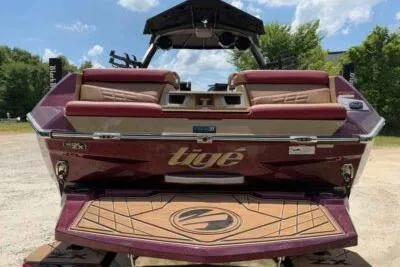 Slide: The Image of 2024 Tigé Ultré 25ZX boat, rear view, maroon color, outdoor setting. - 4