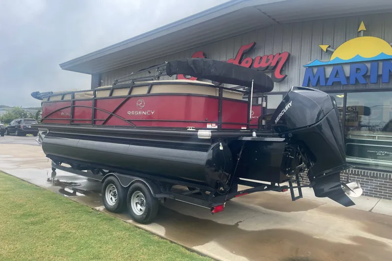 The Image of 2019 Regency 210 DL3 pontoon boat on trailer outside marine store. - 0