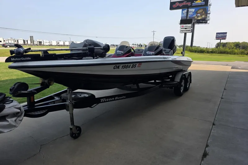 Slide: The Image of 2006 Triton Tr-21X HP DC boat on trailer, parked outdoors near dealership signs. - 2